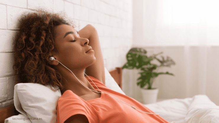 Persona relajándose en el sofá con auriculares escuchando un audiolibro con Audible.