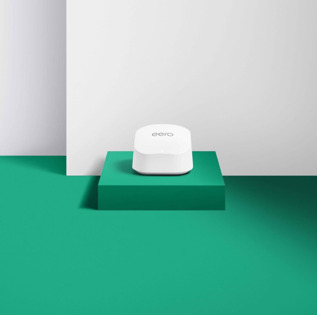 Router Wi-Fi de malla eero 6 Plus sobre una superficie decorativa, destacando su diseño moderno y minimalista.