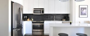 a kitchen with white cabinets and a black stool