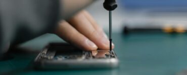 a hand fixing an electronic device using screwdriver