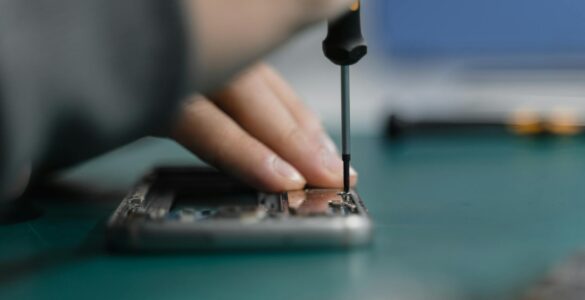 a hand fixing an electronic device using screwdriver