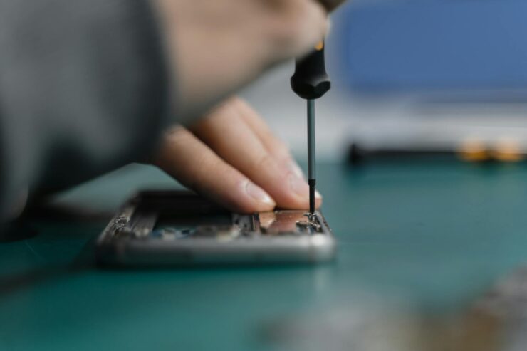 a hand fixing an electronic device using screwdriver