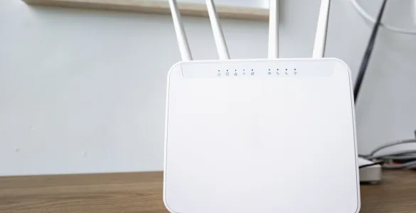 WiFi 2.4 GHz vs. 5 GHz vs. 6 GHz: Guía técnica de bandas y canales 84 Router WiFi moderno de doble banda con cuatro antenas externas omnidireccionales sobre una superficie de madera.