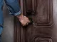 Hombre cerrando la puerta principal con llave, metáfora de seguridad doméstica