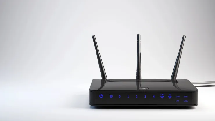 Router WiFi negro con tres antenas externas, LEDs indicadores de puertos LAN, USB y bandas 2.4G y 5G sobre fondo gris neutro