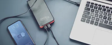 Power bank cargando dos móviles por USB-C junto a un portátil sobre la mesa