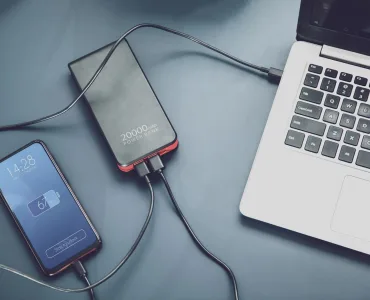 Power bank cargando dos móviles por USB-C junto a un portátil sobre la mesa