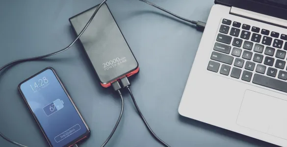 Cómo elegir un power bank: capacidad, vatios y USB-C para móvil y portátil 84 Power bank cargando dos móviles por USB-C junto a un portátil sobre la mesa