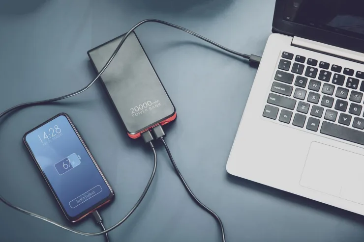 Power bank cargando dos móviles por USB-C junto a un portátil sobre la mesa