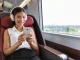Persona usando auriculares con cancelación de ruido en transporte público durante el teletrabajo