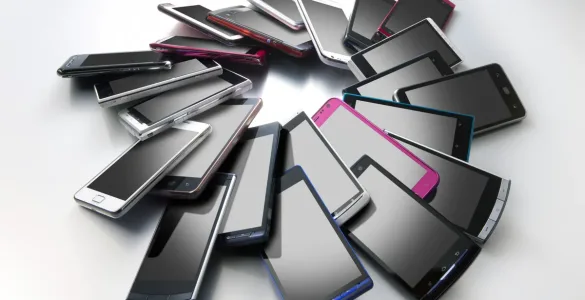 Varios smartphones de distintos colores colocados en círculo sobre una superficie gris