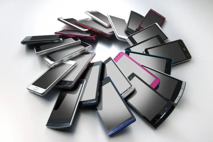 Varios smartphones de distintos colores colocados en círculo sobre una superficie gris
