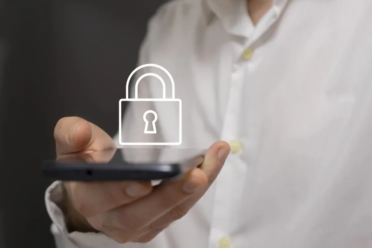 Mano adulta sosteniendo un smartphone con icono de candado, metáfora de privacidad y controles parentales en WhatsApp