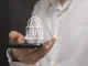 Mano adulta sosteniendo un smartphone con icono de candado, metáfora de privacidad y controles parentales en WhatsApp
