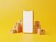 Ilustración de un smartphone genérico con la pantalla en blanco junto a cajas de cartón sobre fondo amarillo
