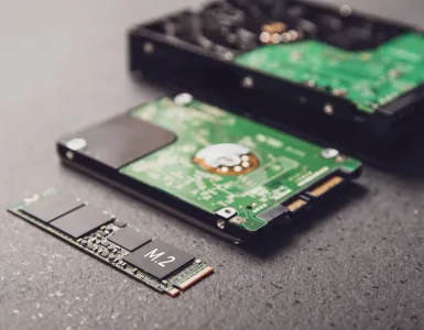 Comparativa visual de un SSD de estado sólido y un disco duro HDD sobre un escritorio de teletrabajo